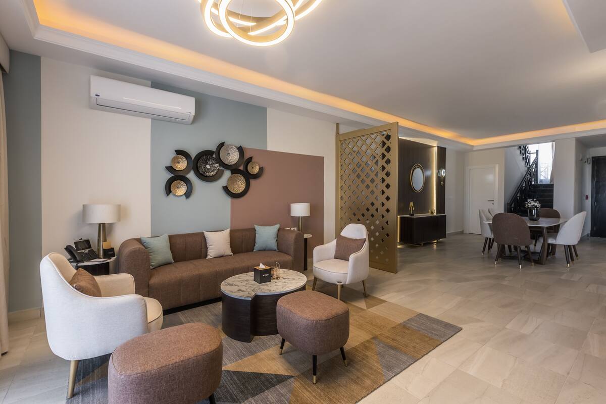 A modern living room with a sofa, armchairs, a coffee table, and a dining area with a table and chairs.