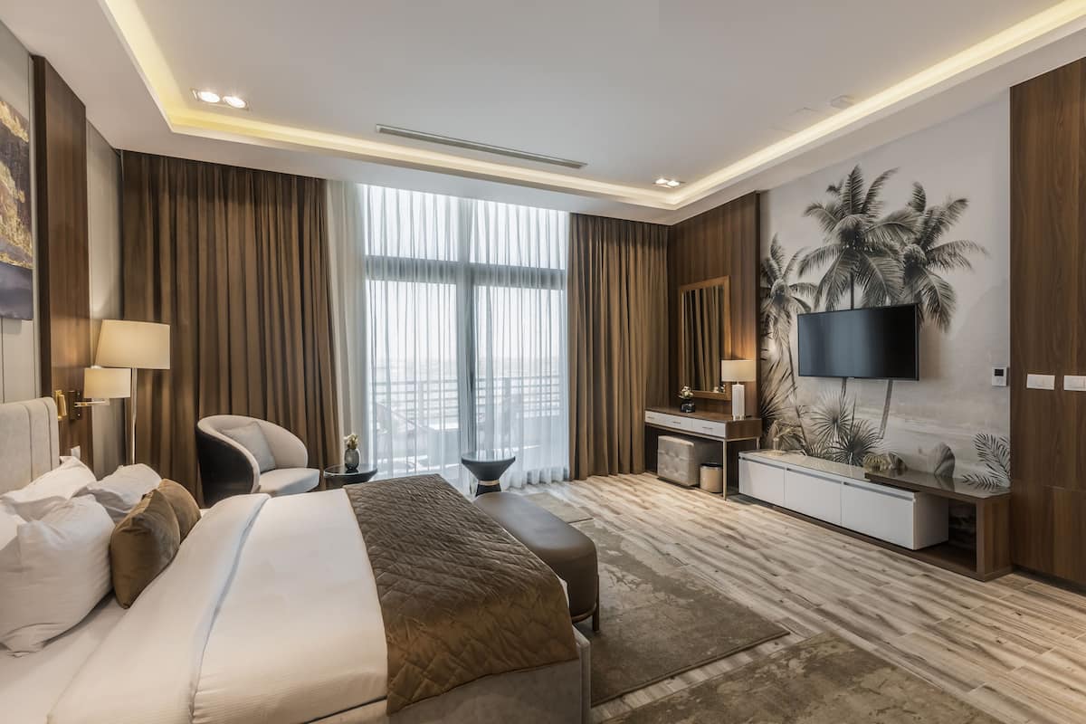 A modern hotel room with a large bed, a desk, and a television.