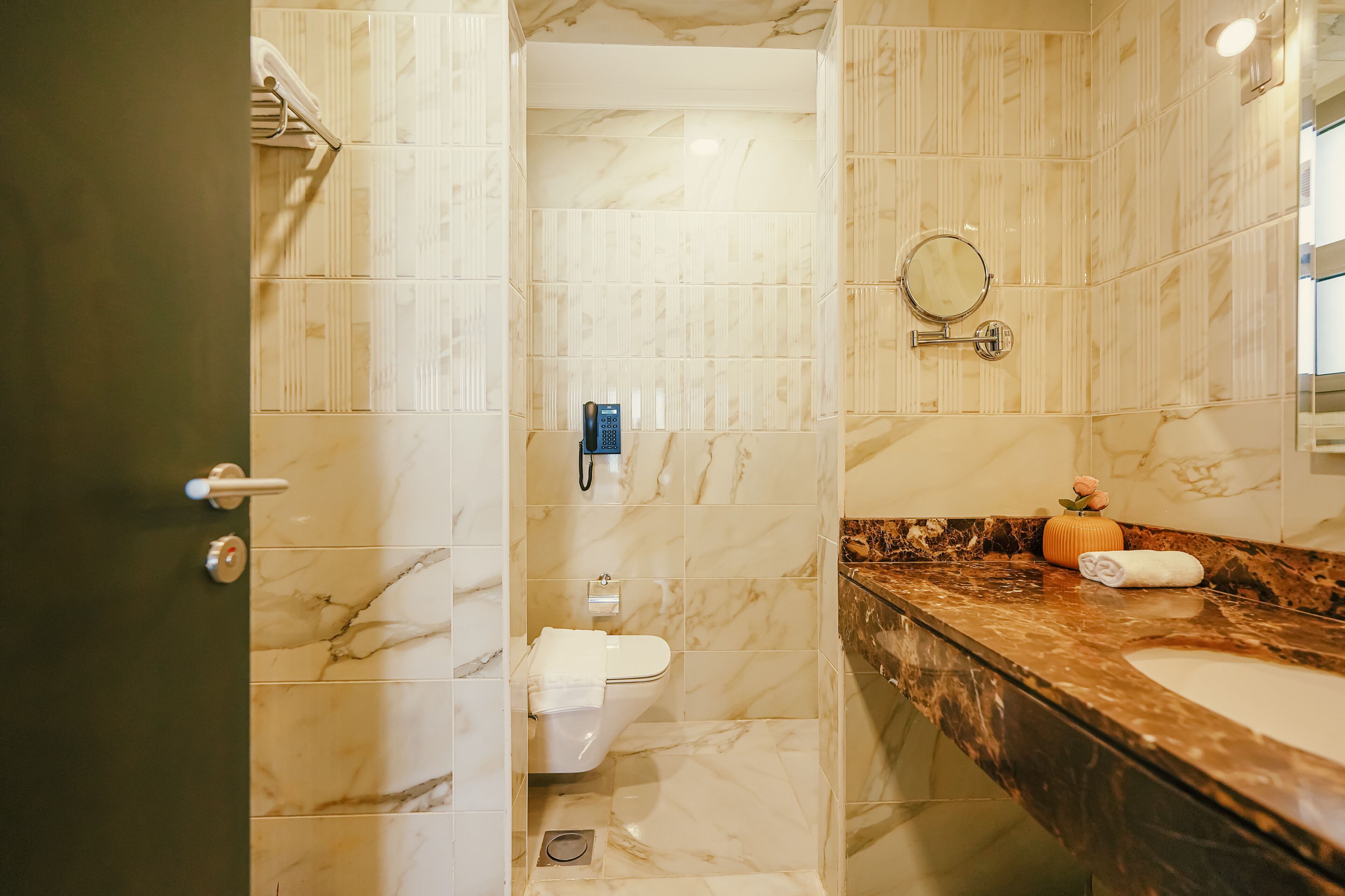A bathroom with a marble floor, a white toilet, a sink with a marble countertop, and a mirror.