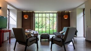 Una sala de estar con dos sillones, un sofá, una mesa de centro y un televisor sobre un mueble.