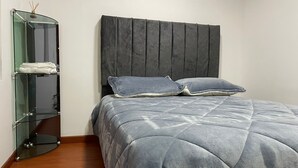 A bedroom with a bed, a glass cabinet, and a wooden floor.