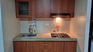 A compact kitchen with wooden cabinets, a stainless steel sink, a gas stove, and a microwave.