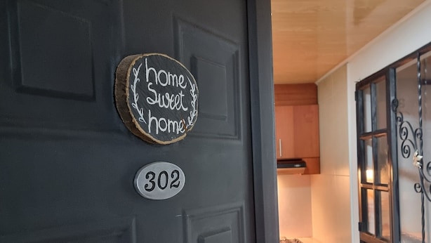 A dark door with a number plate and a sign that says "home sweet home".