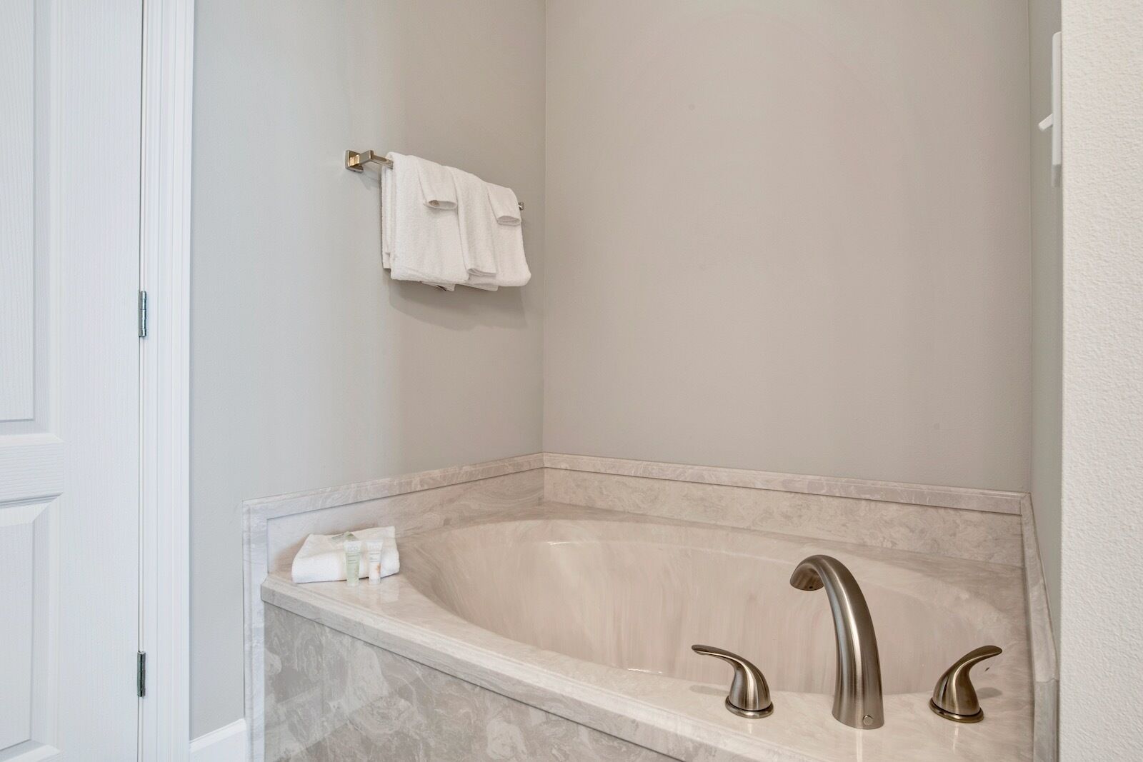Une salle de bain avec une baignoire en marbre, deux robinets chromés et un porte-serviettes sur lequel est posée une serviette blanche.