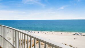 Une plage avec un ciel dégagé, un rivage sablonneux et une rambarde au premier plan.