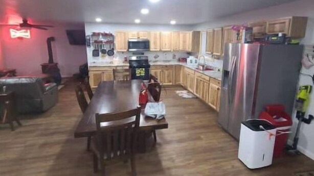 A spacious kitchen with wooden cabinets, a dining table, and a refrigerator. - Hillbilly Haven (Equinunk)