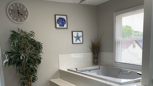 A modern bathroom with a bathtub, a potted plant, and a clock on the wall. - The Seabreeze  (Dayton)