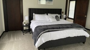 A bedroom with a bed, bedside tables, a ceiling fan, and a window with blinds. - The Seabreeze  (Dayton)