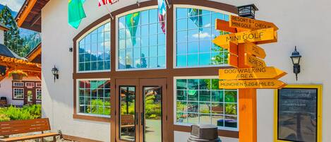 A building with a sign reading "ENTRANCE" and multiple directional signs pointing to amenities like "MINI GOLF" and "DOG WALKING AREA".