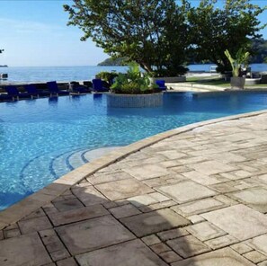 A pool with clear blue water, surrounded by stone tiles and blue lounge chairs. - Chaquacabana Resort & Beach Club (Chaguaramas)