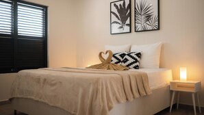 Ein Schlafzimmer mit einem Bett, einem Nachttisch mit Lampe und zwei gerahmten Pflanzenbildern an der Wand.