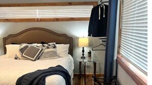 A hotel room with a bed, bedside table, lamp, chair, and window with blinds. - 'Suitest' Spot Downtown. (Anchorage)