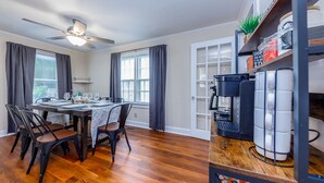 A dining area with a wooden table and chairs, a ceiling fan, and a coffee machine. - Amazing 3 BR House / Downtown New Bern / Sleeps 8 (New Bern)