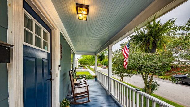 A porch with a blue door, rocking chairs, a potted plant, and an American flag. - Amazing 3 BR House / Downtown New Bern / Sleeps 8 (New Bern)