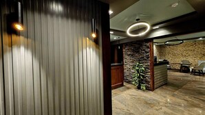 A reception area with a stone wall, wooden paneling, and a reception desk. - Grand Bayan Hotel at Nile Plaza (Cairo)