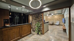 A modern reception area with a wooden counter, stone wall, and a potted plant. - Grand Bayan Hotel at Nile Plaza (Cairo)