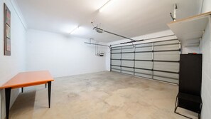Eine Garage mit Betonboden, geschlossenem Garagentor und einem Tisch mit Stuhl.