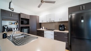 Eine moderne Küche mit einem Edelstahl-Kühlschrank, einem eingebauten Ofen und einer Kaffeemaschine.