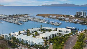 A marina with multiple docks, a variety of boats, and a coastal town with modern buildings. - Apartment By The Harbour (Townsville)