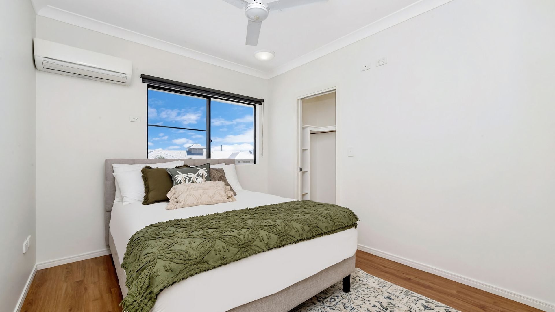 A bedroom with a bed, a window, a ceiling fan, and a door.