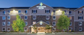 Ein mehrstöckiges Hotel mit einem zentralen Eingang, erkennbar an einem Schild mit der Aufschrift 'Woodspring Suites'.