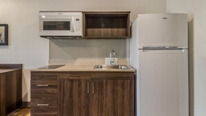 Una cocina equipada con microondas, lavamanos y refrigerador.