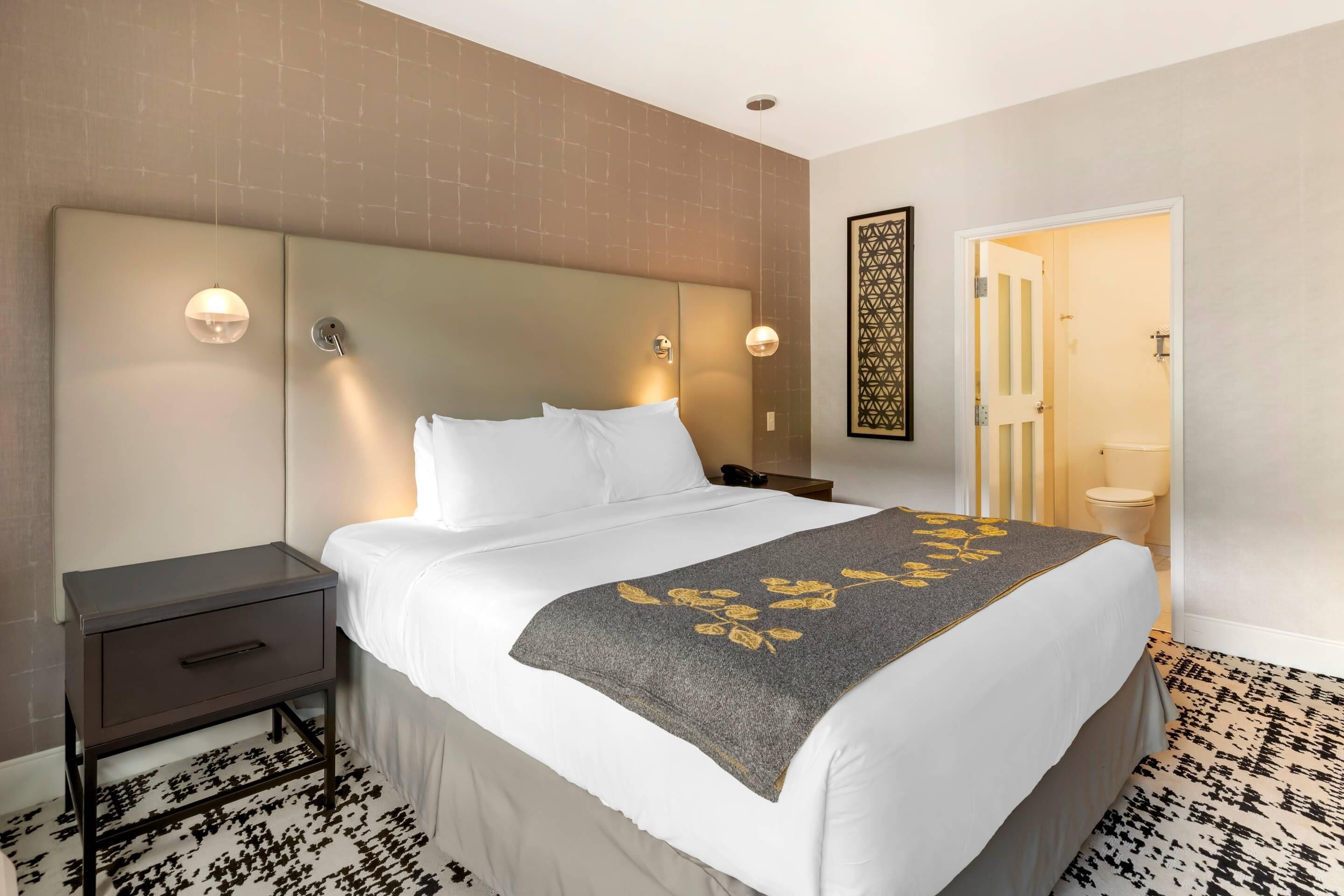 Ein Hotelzimmer mit Bett, Nachttisch und einer Badezimmertür.