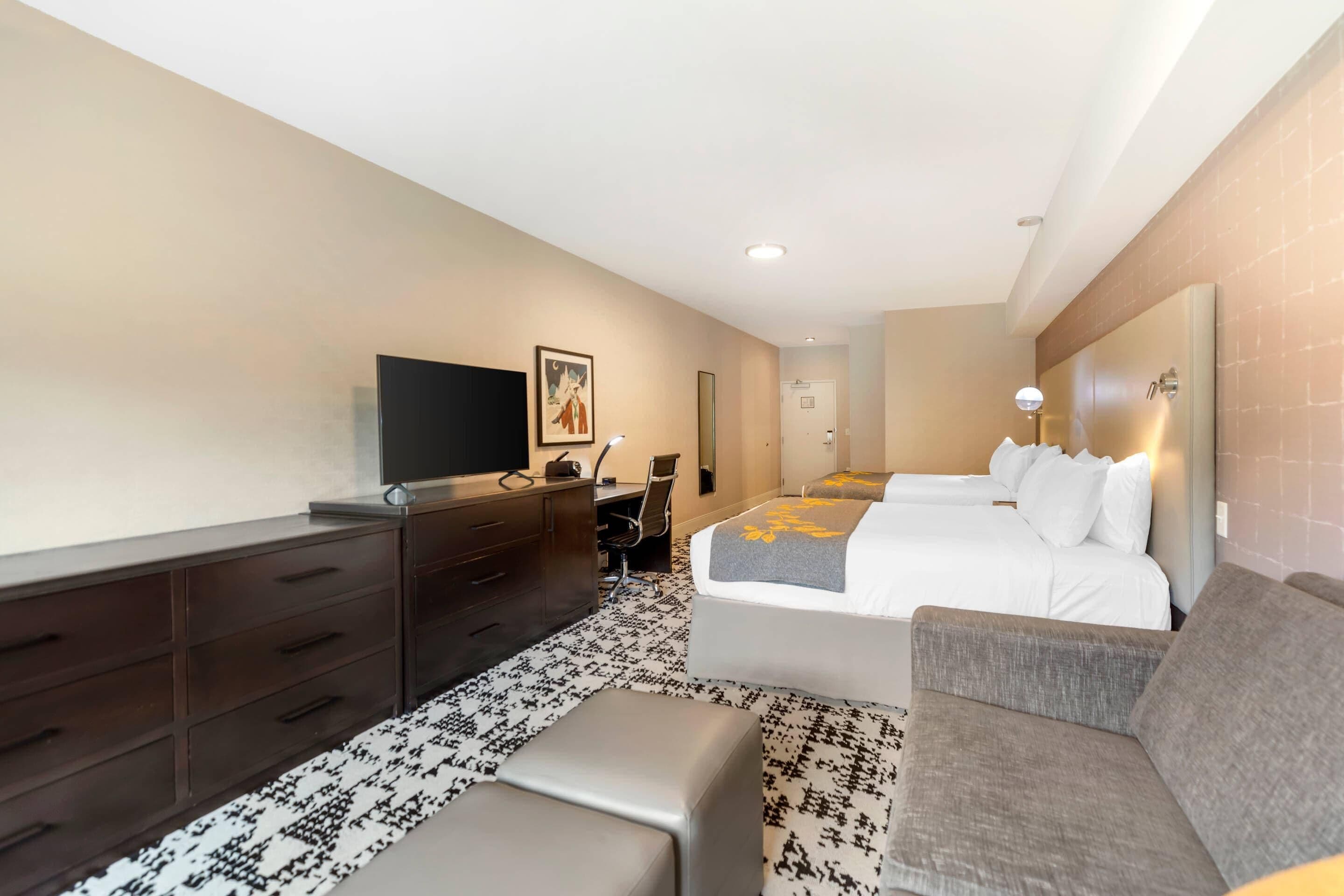 Una habitación de hotel con cama, sofá, escritorio, televisión y baño.