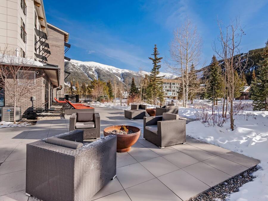 A patio area with outdoor furniture, a fire pit, and a view of snow-covered mountains.