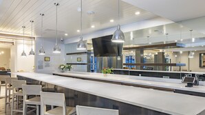 Una cocina moderna con una encimera larga, luces colgantes y taburetes de bar.