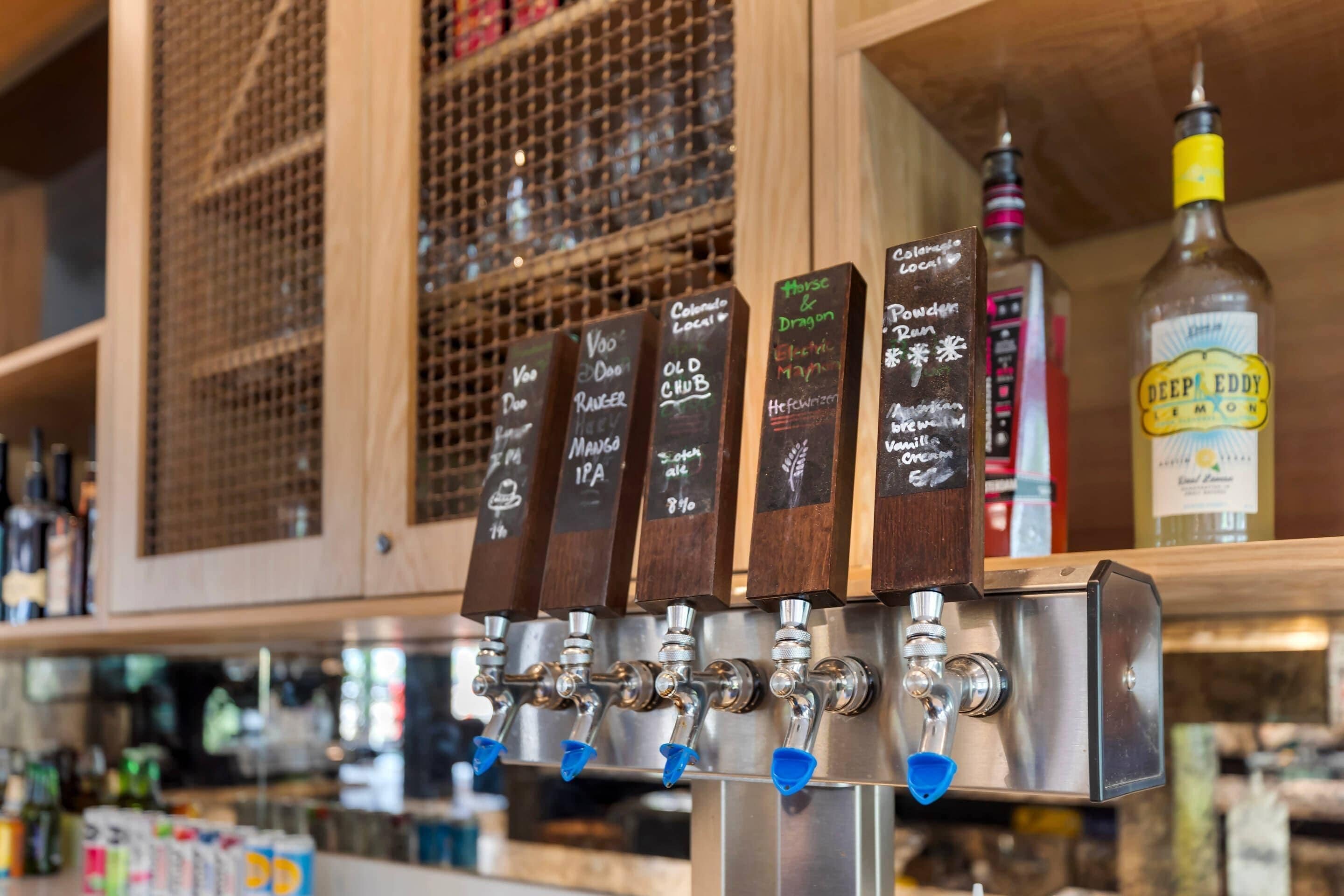 A bar with multiple taps labeled with different beer types and a bottle of Deep Eddy Lemon.