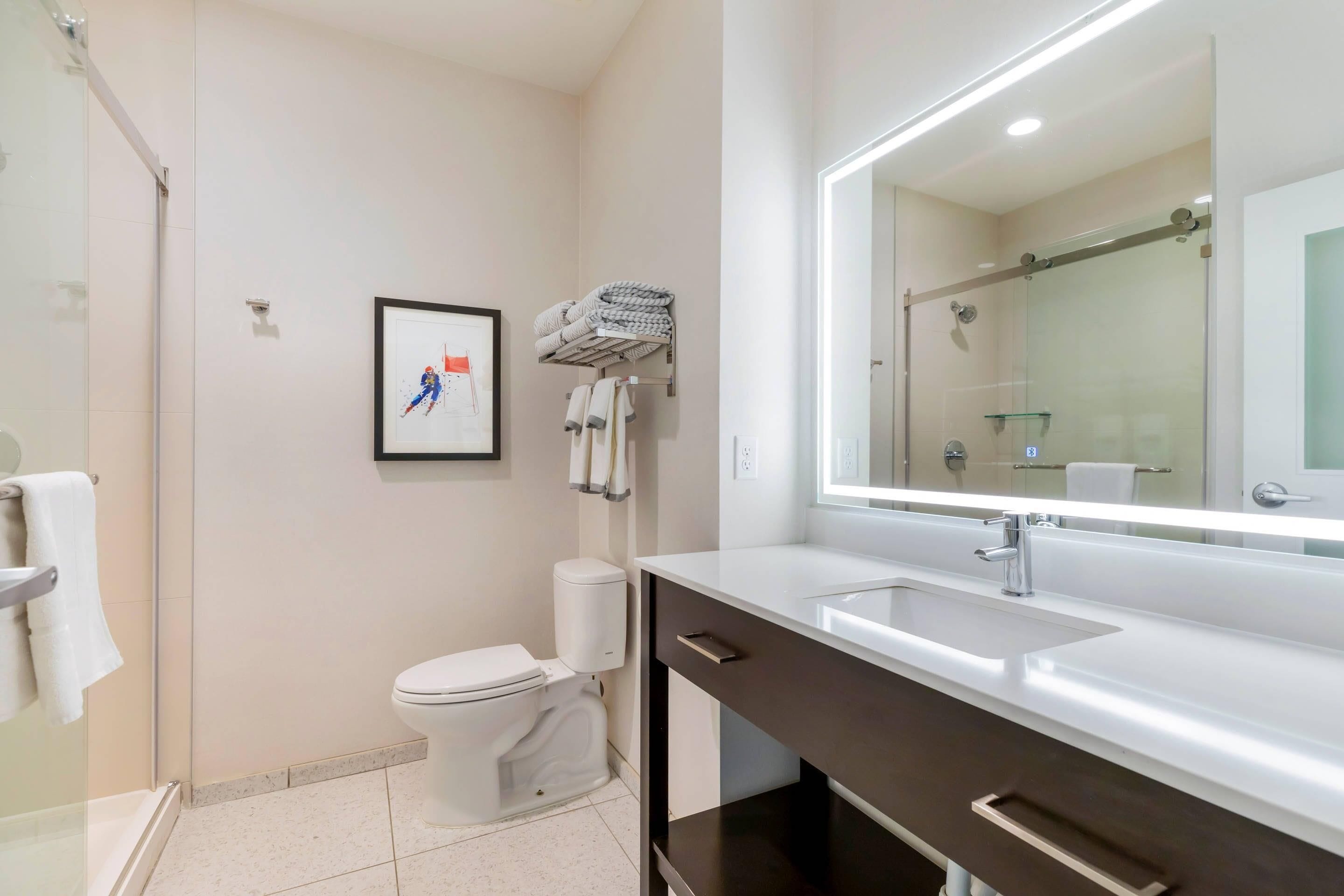 A modern bathroom with a toilet, sink, and shower.