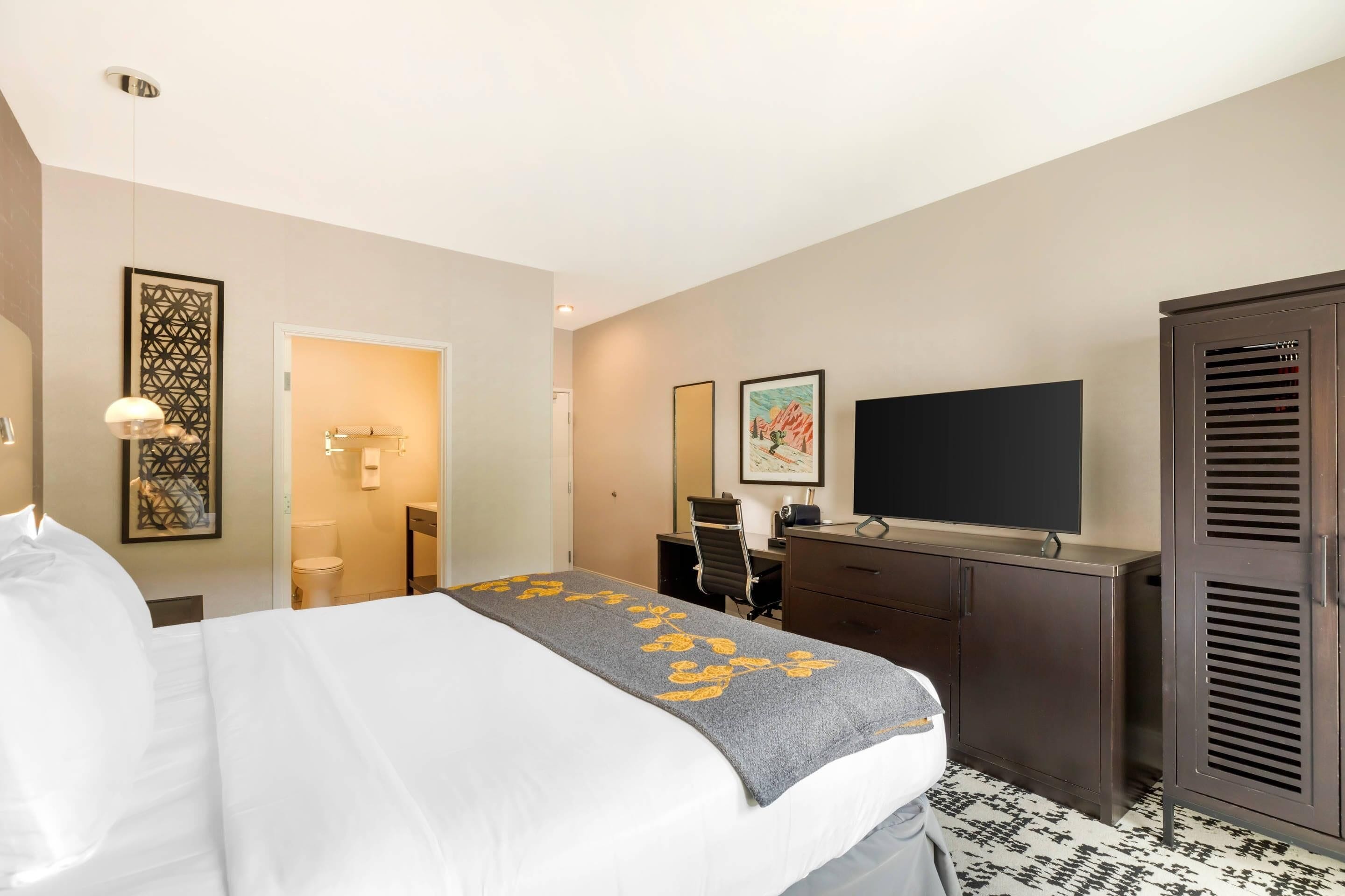Een hotelkamer met een bed, een bureau, een televisie en een kledingkast.