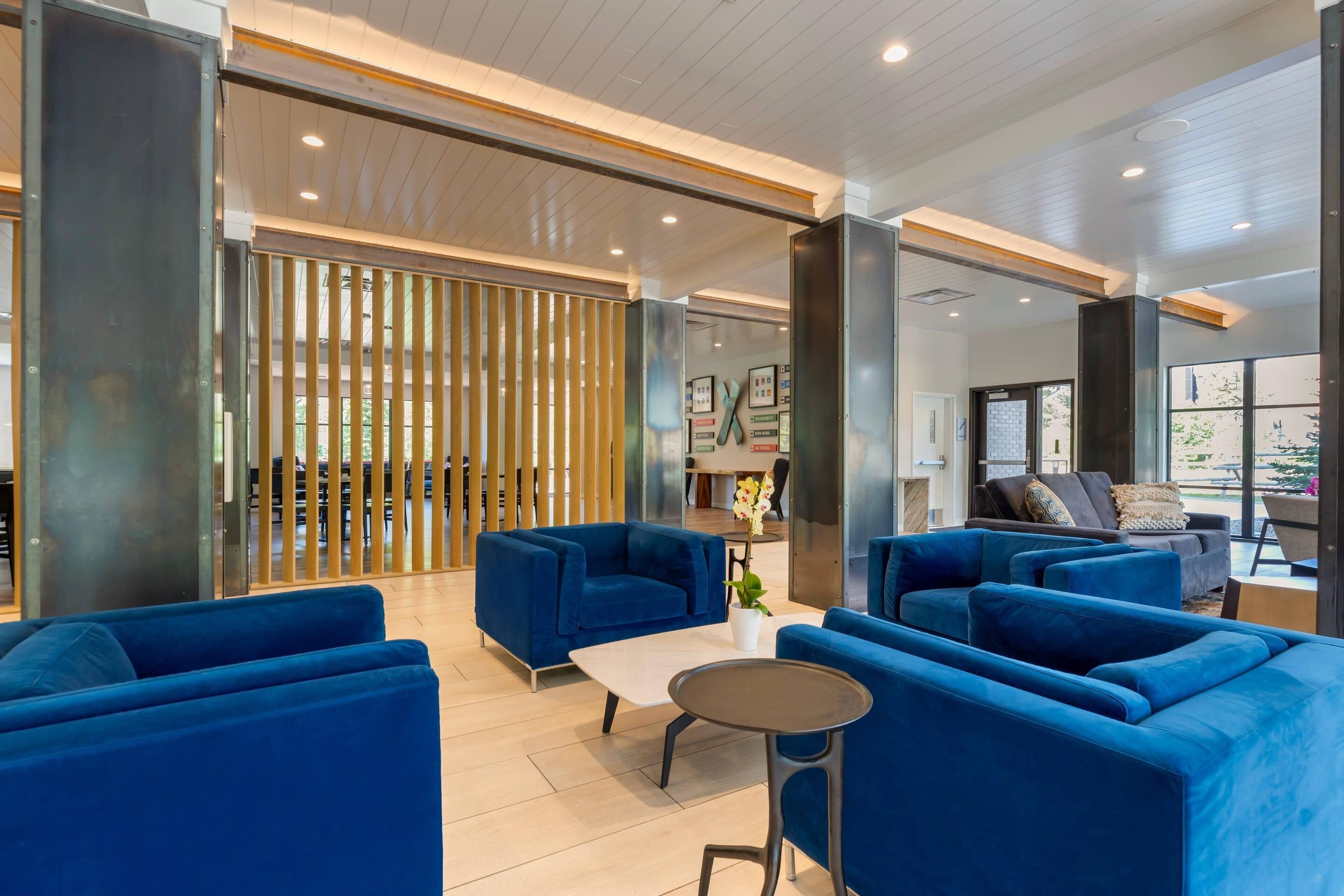 A modern lobby with blue sofas, a small table, and a wooden partition.