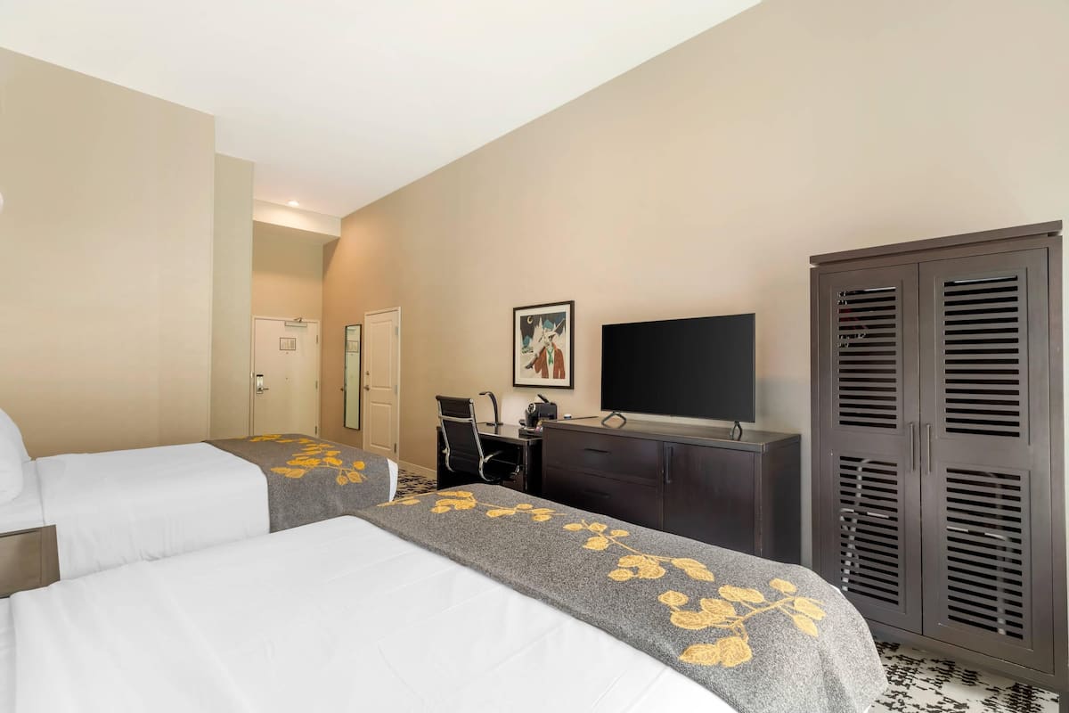 Een hotelkamer met twee bedden, een bureau, een televisie en een kledingkast.