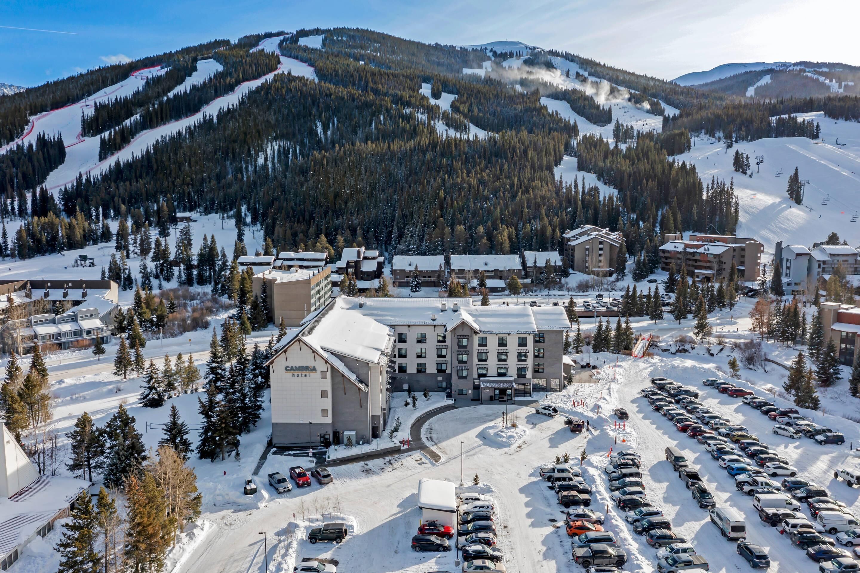 A snow-covered parking lot with multiple buildings, including a hotel with a prominent sign.
