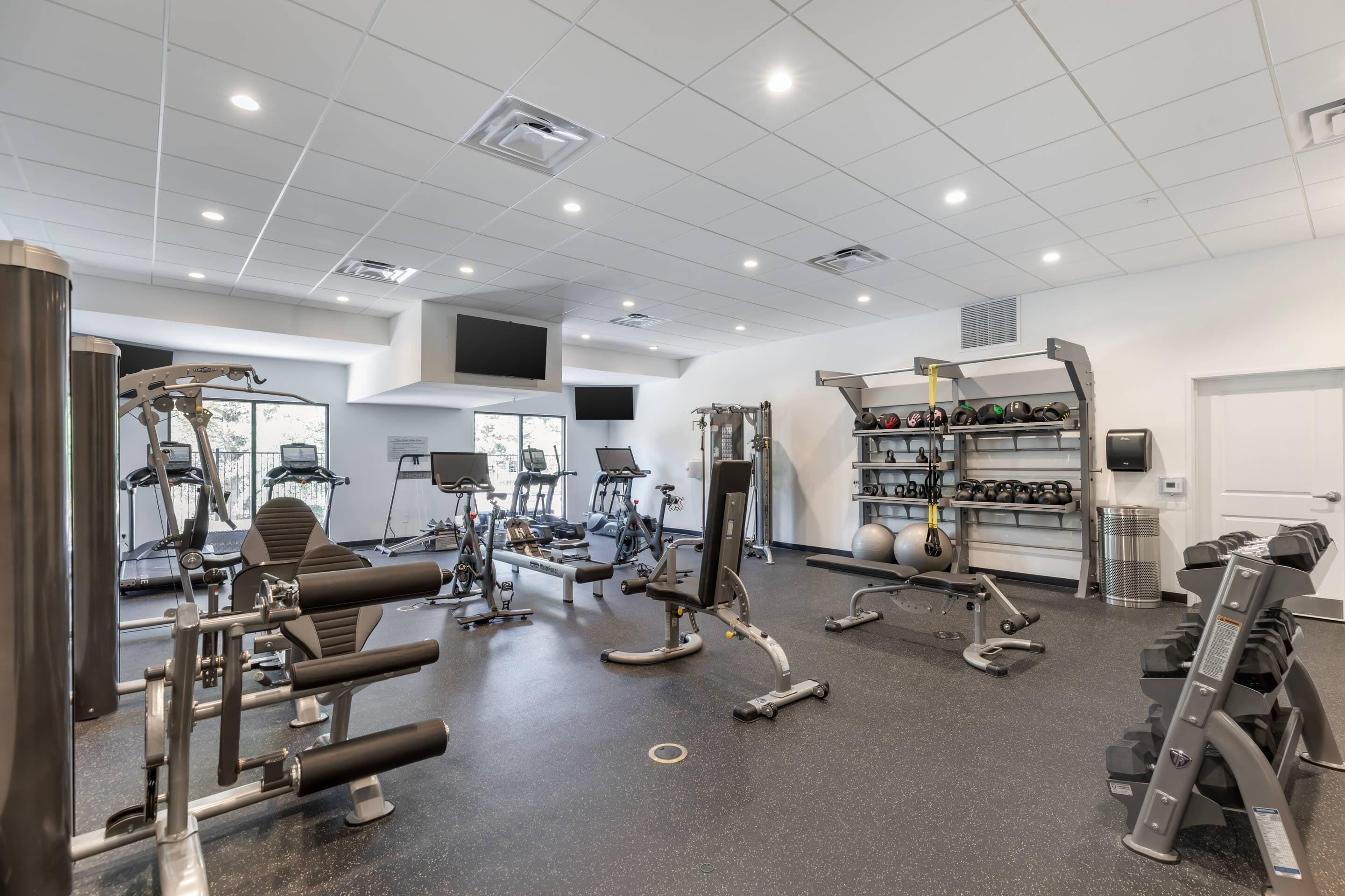 A gym with various exercise equipment, a mirrored wall, and a door.