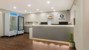 A hotel reception area with a modern design, featuring a reception desk, two glass display cases, and a sign indicating 'Suburban Studios by Choice Hotels' and 'Quality'. - Suburban Studios Millville (Millville)