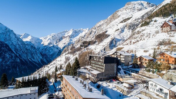 A mountain resort with snow-covered buildings, a ski lift, and a view of snow-capped mountains.