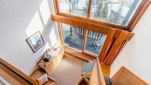 Una habitación con techos altos y un amplio ventanal con vistas a un paisaje nevado.