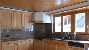 Une cuisine avec des armoires en bois, un plan de travail en granit et un lave-vaisselle.