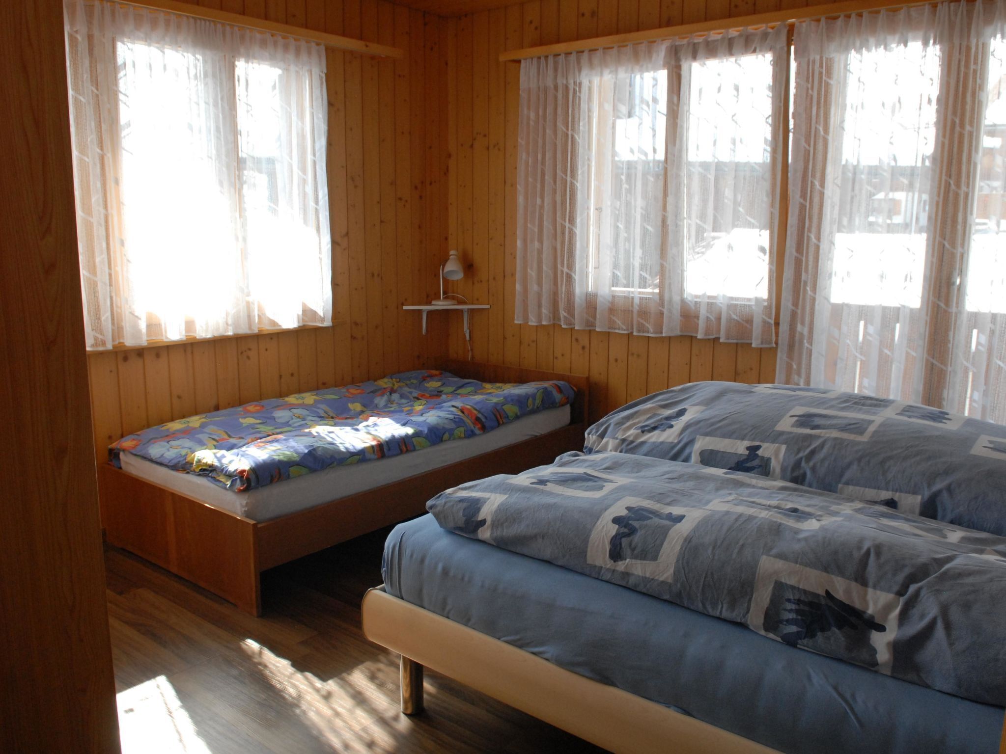 Een kleine, gezellige kamer met houten wanden en twee bedden.