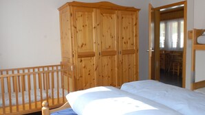 Une chambre à coucher avec une armoire en bois, un lit avec une literie blanche et un berceau en bois.