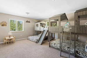 Quarto infantil com beliches, escrivaninha e janela.