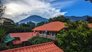 A building with a red roof, surrounded by lush greenery and mountains in the background.
