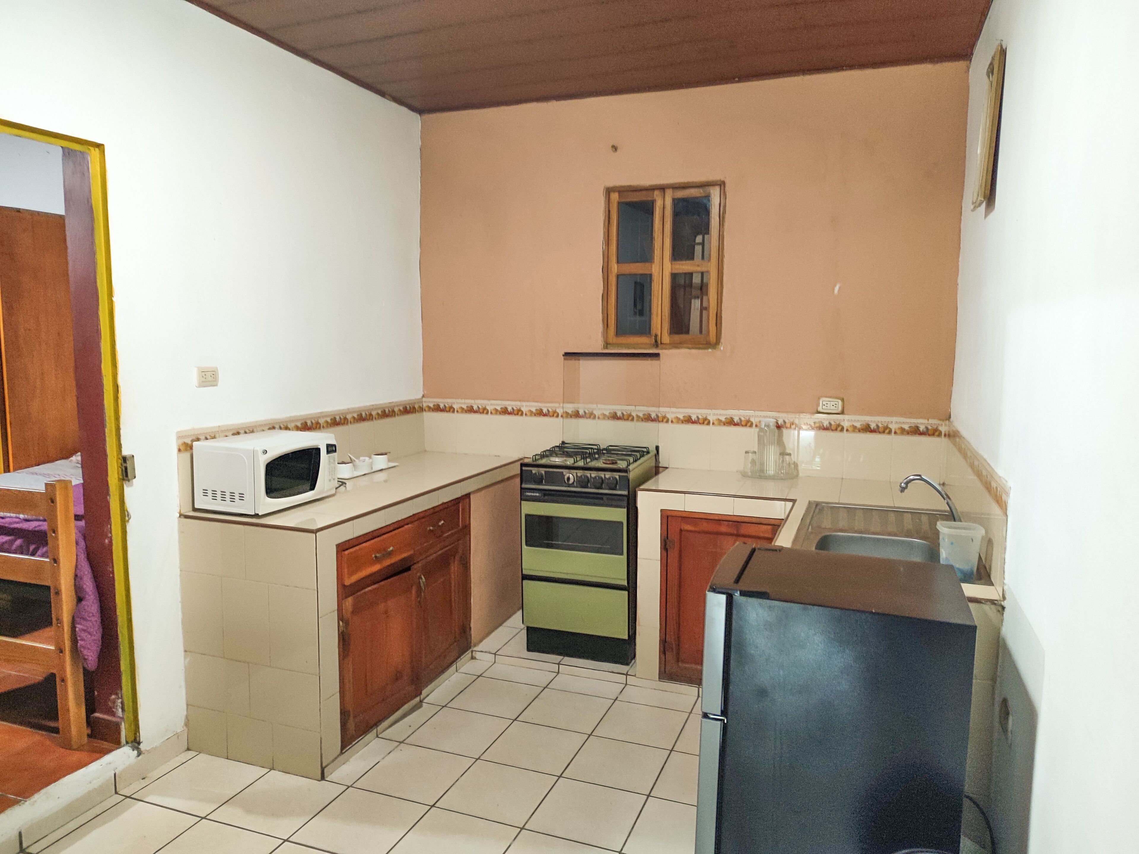 A compact kitchen with a microwave, gas stove, and sink.