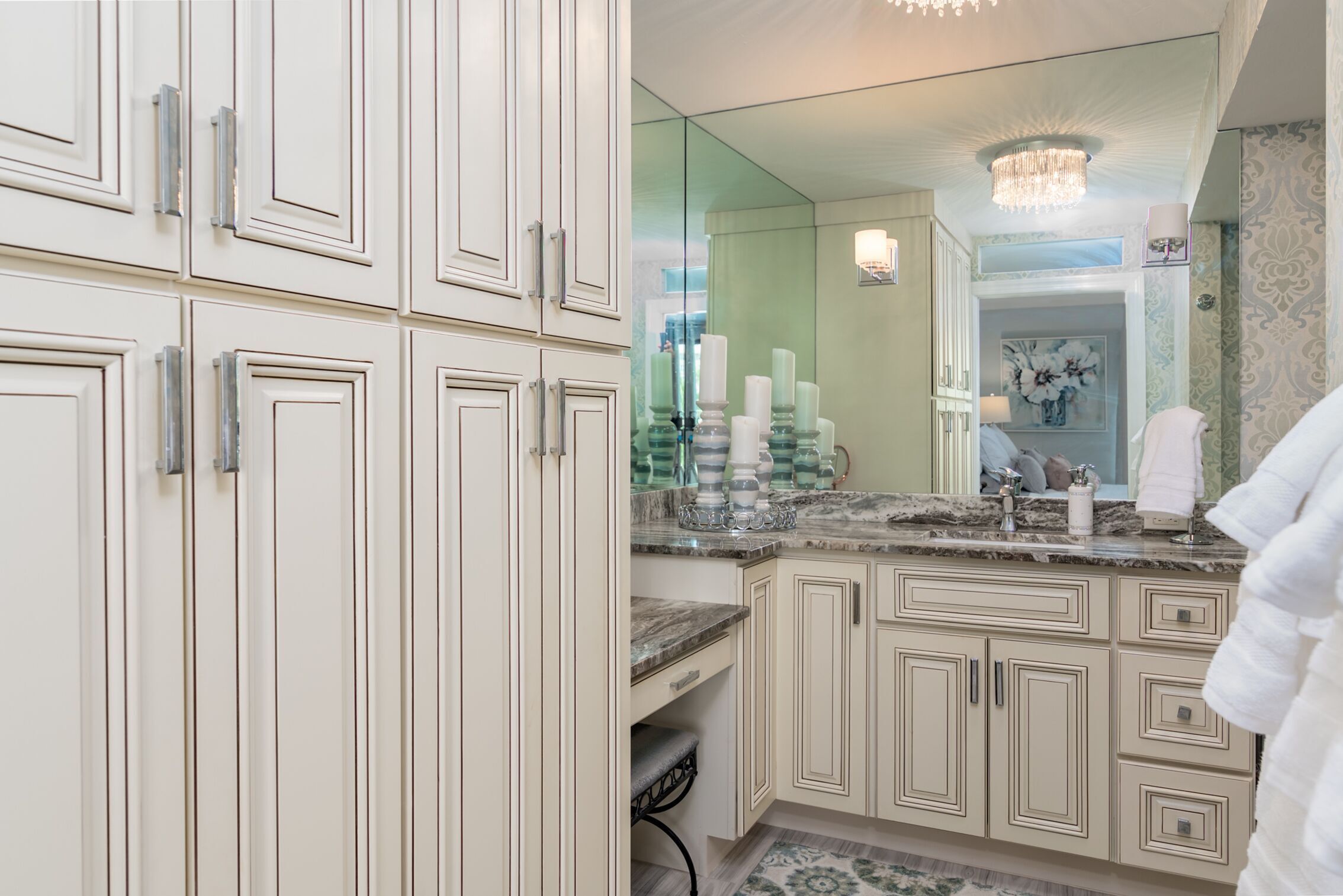 A bathroom with white cabinetry, a marble countertop, and a large mirror.