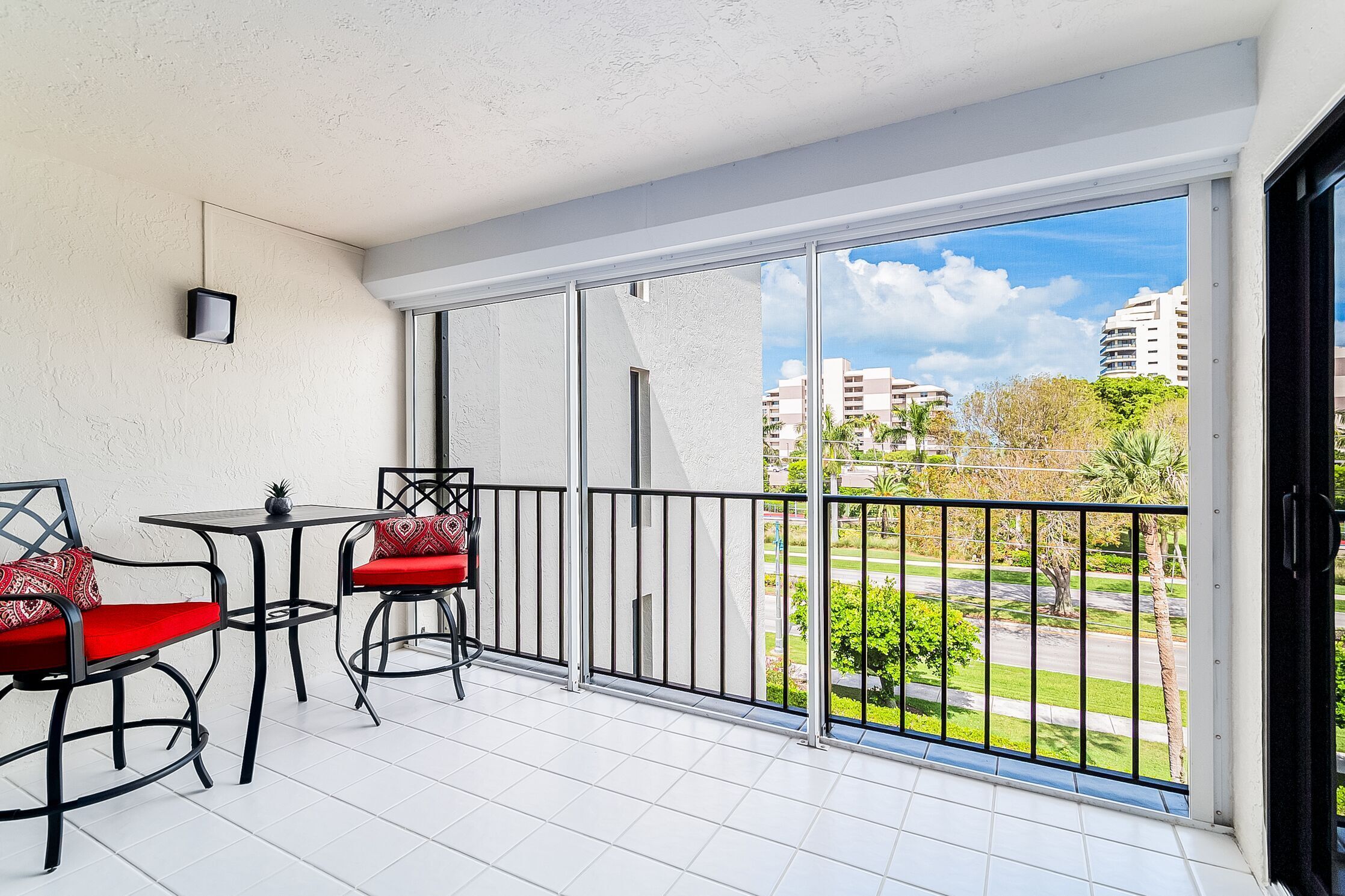 A balcony with two chairs and a table, a view of a cityscape, and a clear sky.