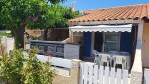Ein Wohnhaus mit Ziegeldach, einer überdachten Terrasse mit Gartenmöbeln und einem weißen Zaun.