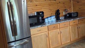 Cucina con mobili in legno, frigorifero in acciaio inossidabile, forno a microonde, macchina del caffè e tostapane.